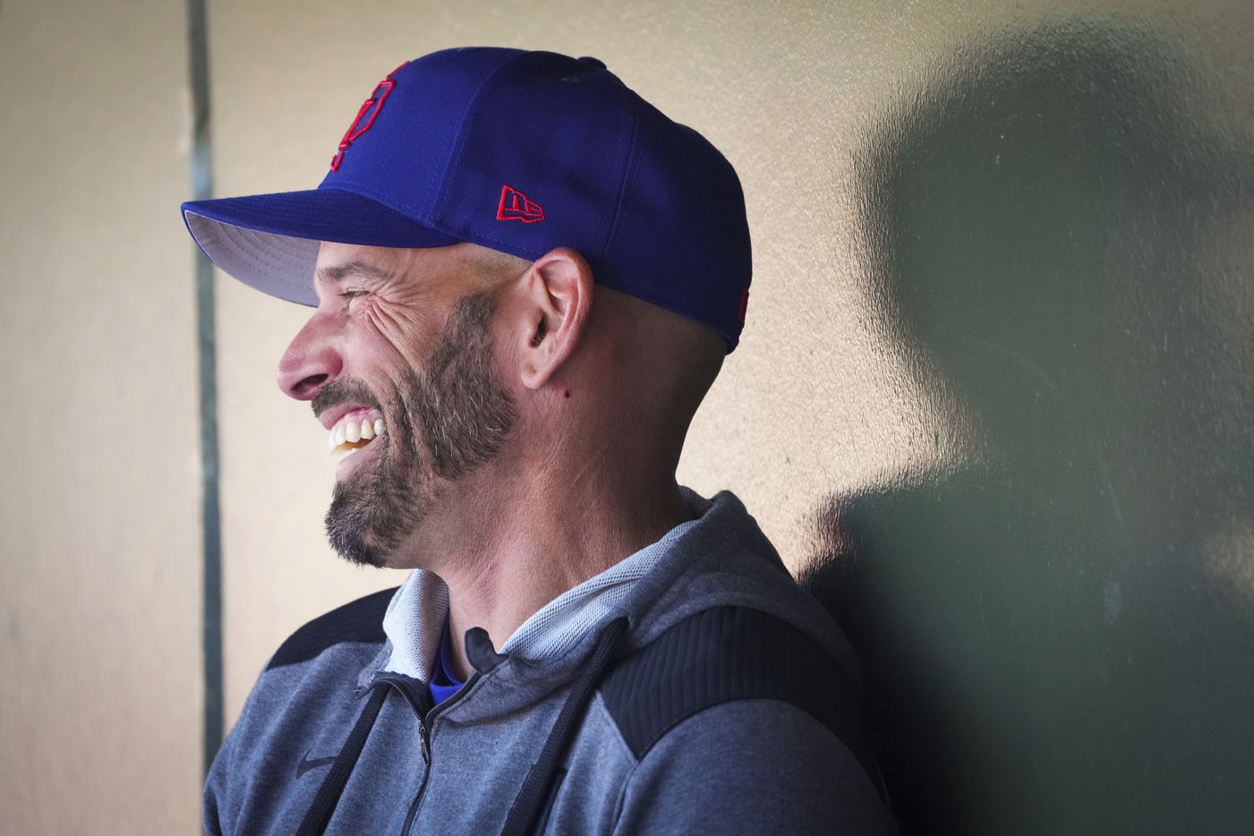 Texas Rangers manager Chris Woodward laughs in the dugout before a spring training game...