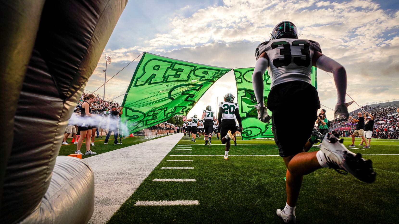 Prosper’s TJ Jones (33) runs out of the tunnel with teammates before a season-opening high...