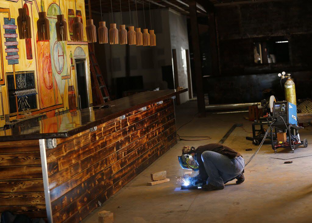 Welder Stephanie Dibble constructs a foot rail for the bar  (left) at Intrinsic Smokehouse &...