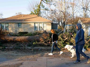 Neighborhood residents Marquette, left, and Fred Vega walks their dog Breck as they observe...