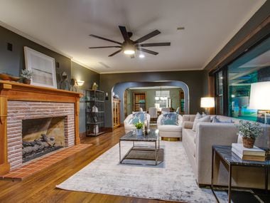 Dark gray living room featuring a red-brick fireplace with a midcentury oak mantle and wood...
