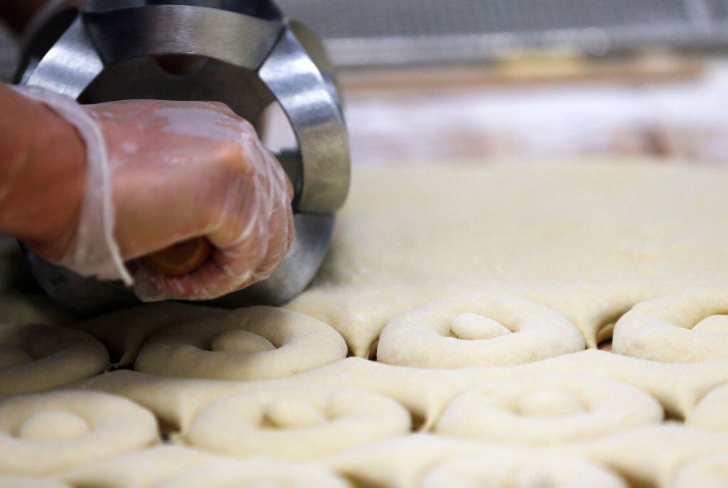 Jorge Magdaleno, of Aubrey cuts donuts in preparation of a grand opening at Hurts Donut Co....
