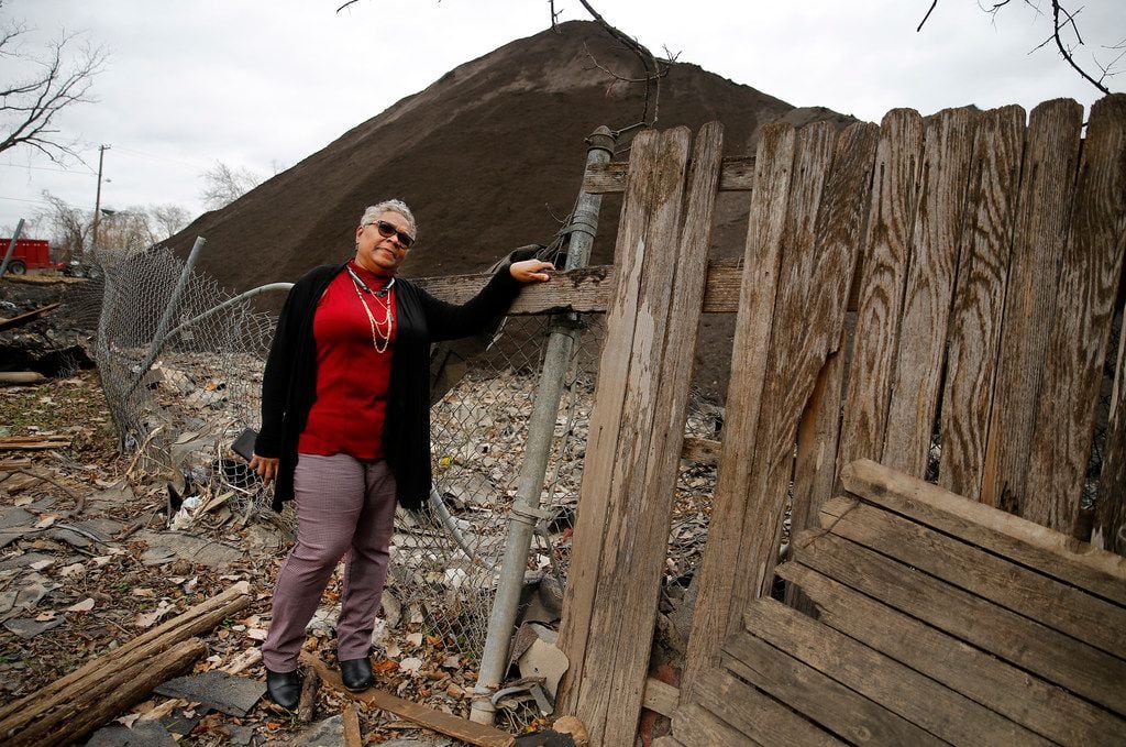 Homeowner Marsha Jackson looks over her damaged fence at the large mounds of shredded roofing shingles.  She is tired of the late night and early morning grinding of shingles that takes place outside her bedroom window in southeast Dallas, 