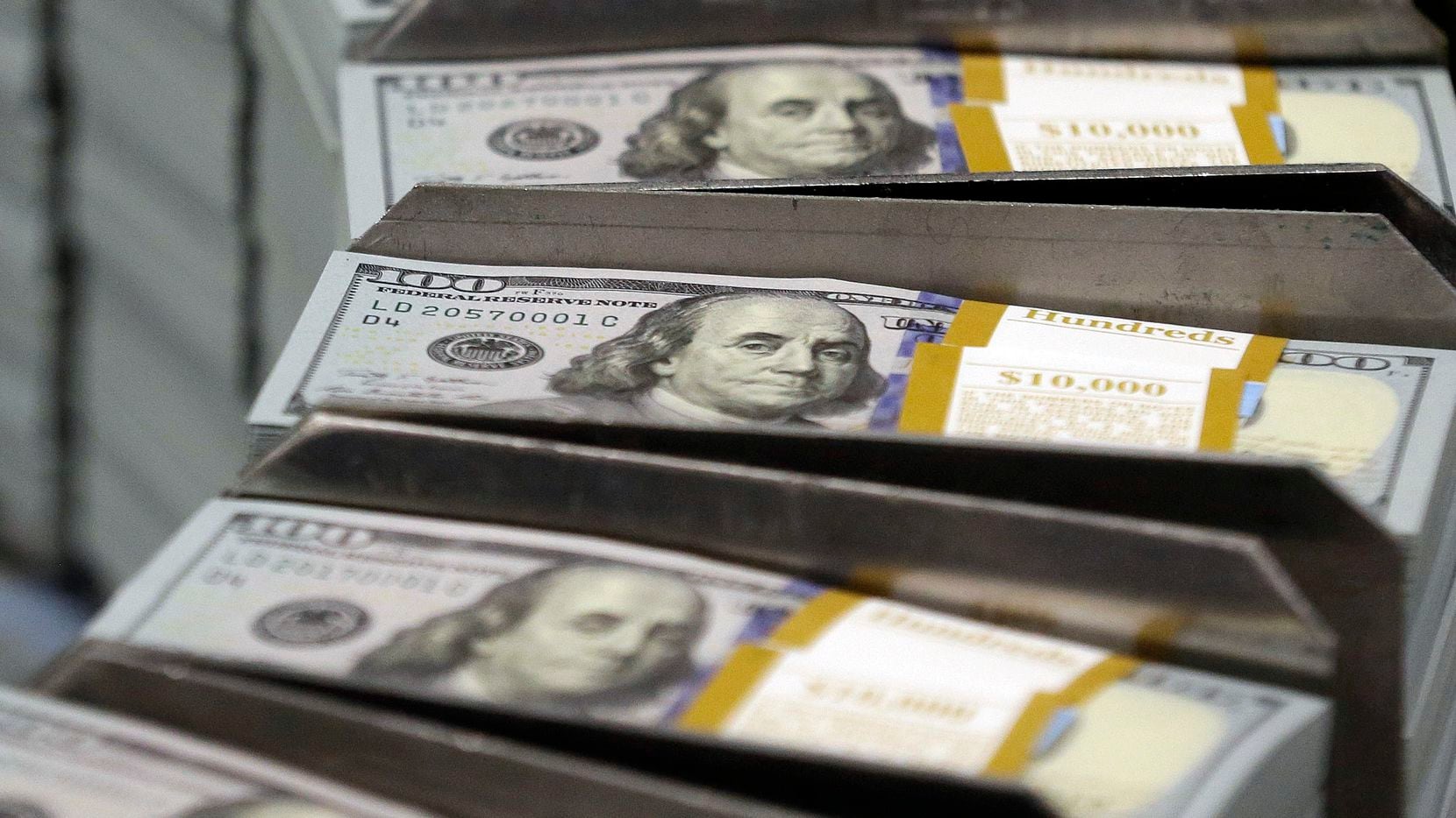 Freshly cut stacks of $100 bills make their way down the line at the Bureau of Engraving and...