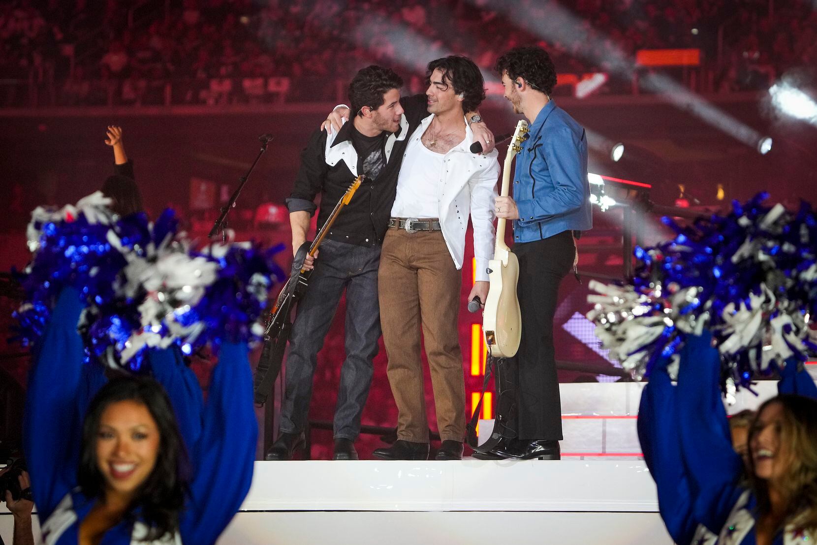 The Jonas Brothers perform with the Dallas Cowboys cheerleaders during halftime of an NFL...