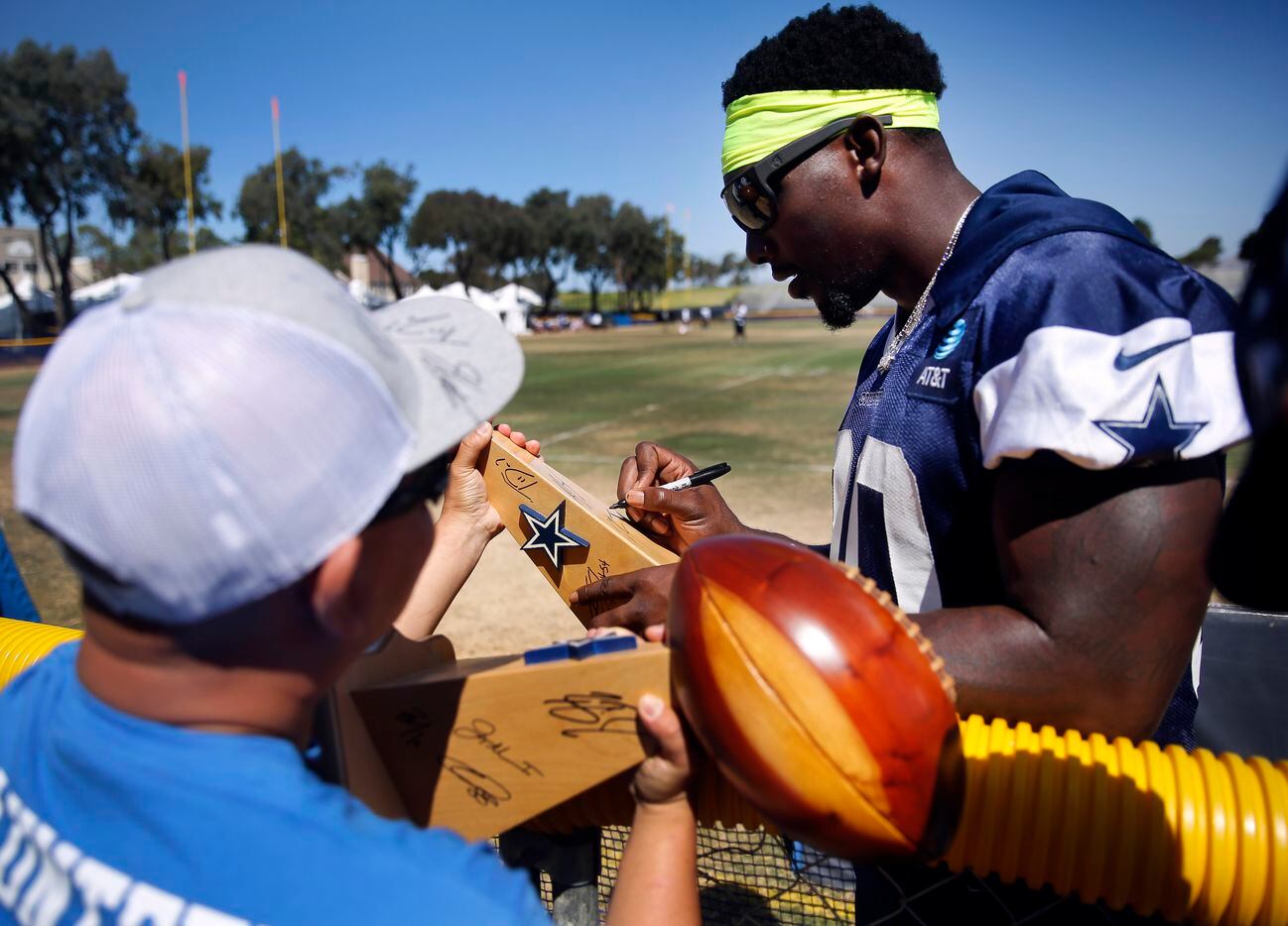 Dallas Cowboys defensive end DeMarcus Lawrence signs wooden Super Bowl trophies for a...