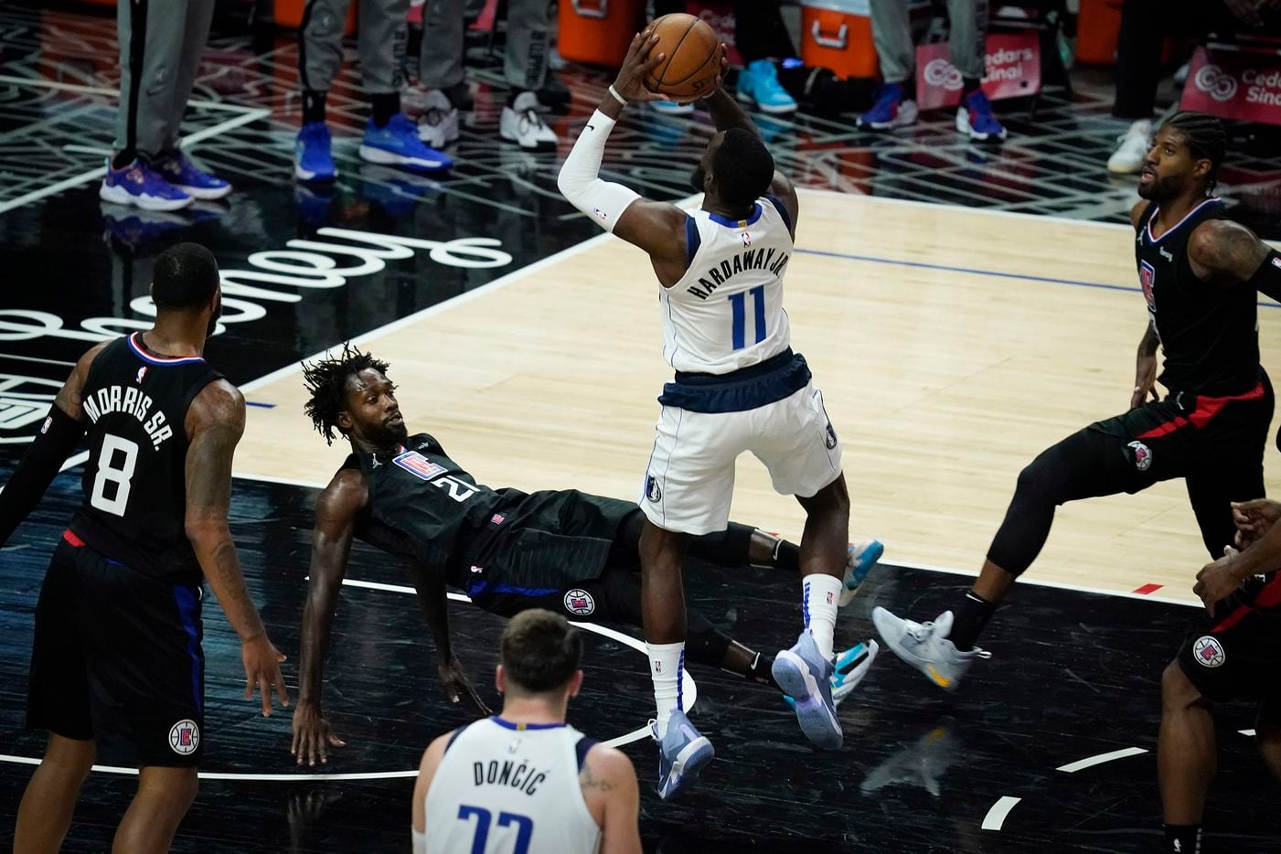 LA Clippers guard Patrick Beverley (21) falls to the ground as he picks up a foul on a drive by Dallas Mavericks forward Tim Hardaway Jr. (11) during the second half of an NBA playoff basketball game at Staples Center on Tuesday, May 25, 2021, in Los Angeles.