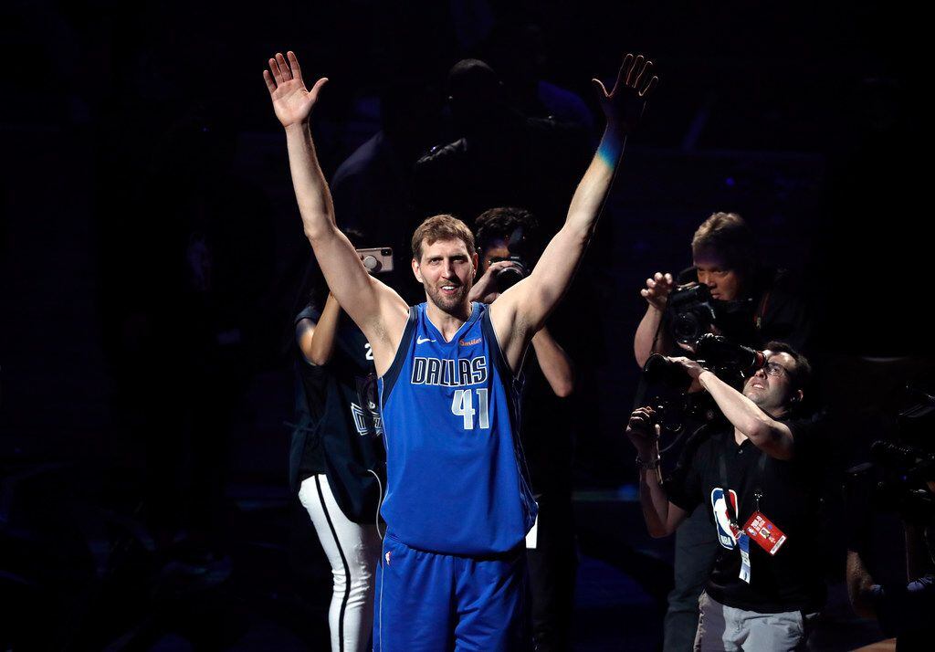 Dallas Mavericks' Dirk Nowitzki acknowledges cheers from fans as he walks off the court...
