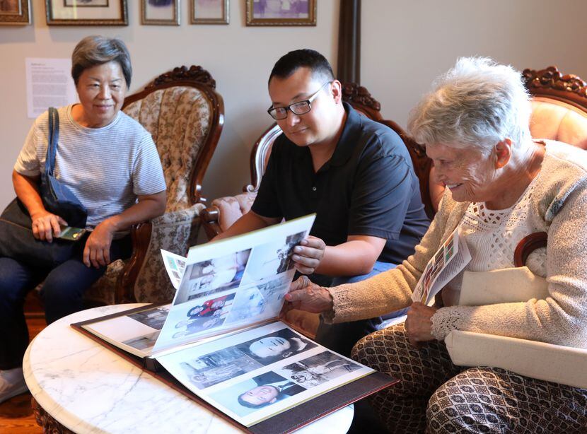 Cindy Chan, left, Thomas Jung, and Harryette Ehrhardt look through memorabilia during The...