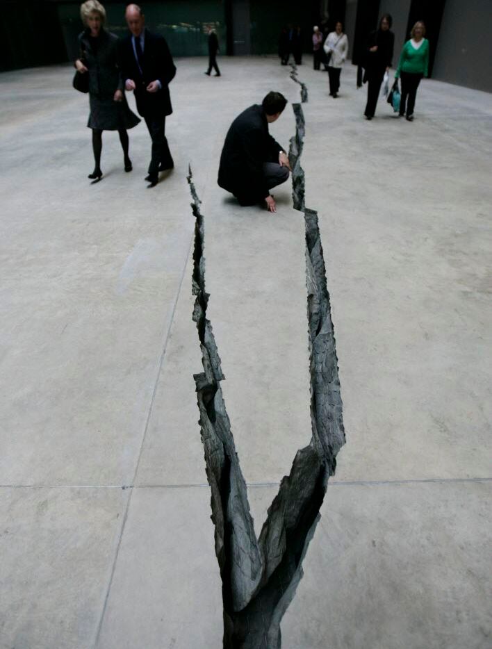  A visitor examines a crack in the floor titled 