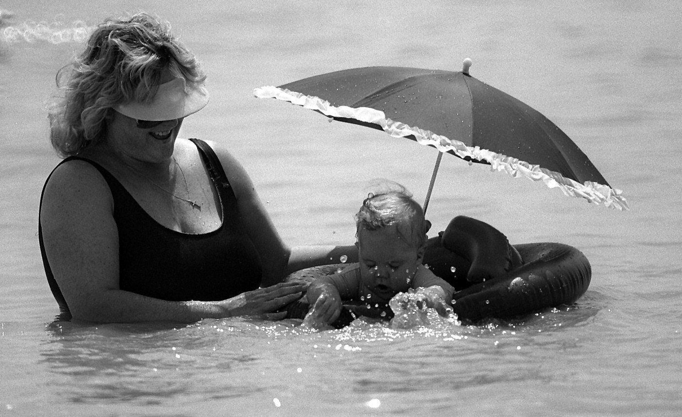 Regina McDonald, smiles as her 8-month-old daughter, Alyssa McDonald, splashes water in the beach of Cedar Hill State Park at Joe Pool Lake. Photograph taken May 31, 1994.