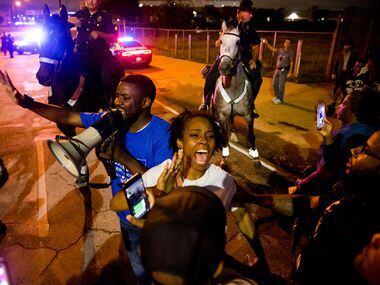 Dominique Alexander (left) attempts to control protesters as they march in the streets on...