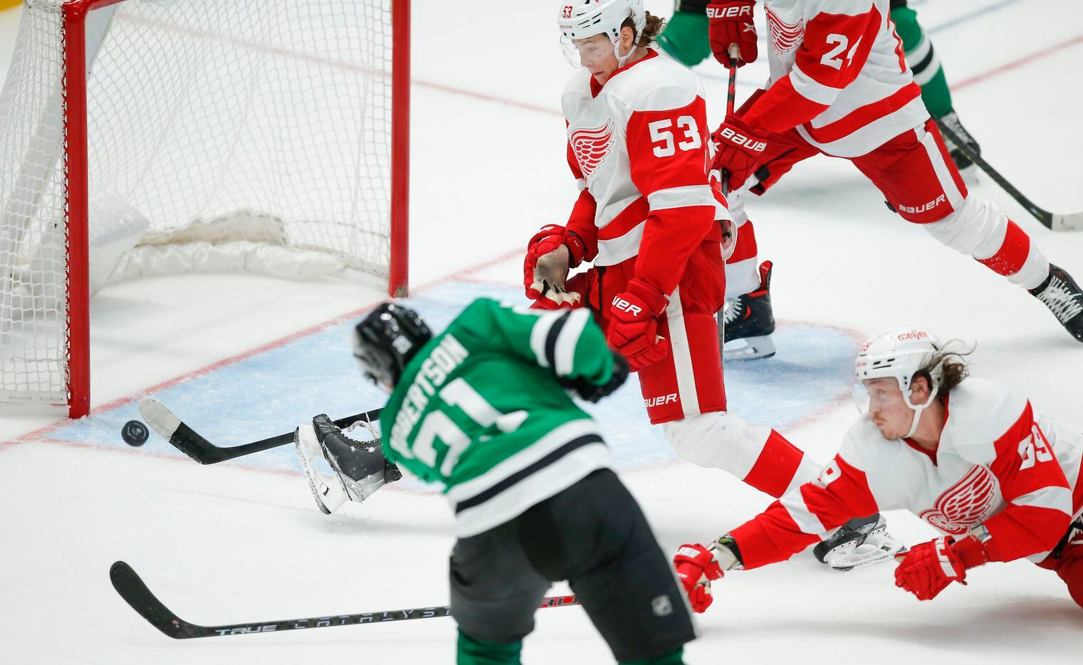 Dallas Stars forward Jason Robertson (21) attempts a shot on an empty net as Detroit Red Wings defenseman Moritz Seider (53) and  forward Tyler Bertuzzi (59) defend during the third period of an NHL hockey game, Tuesday, November 16, 2021. Dallas won 5-2. (Brandon Wade/Special Contributor)