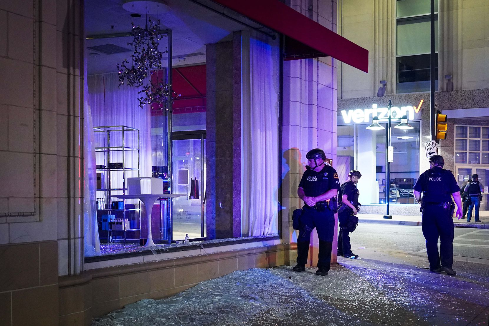 Dallas police stand guard amidst broken glass after windows were smashed at the Nieman...