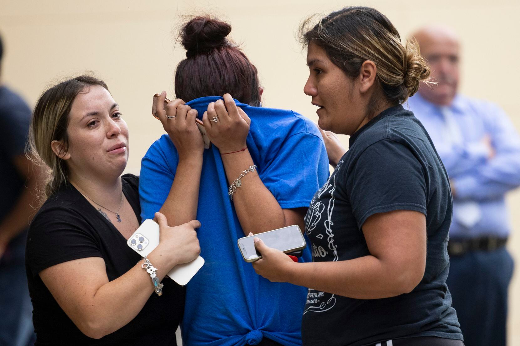 A woman is consoled after coming out of the Willie de Leon Civic Center in Uvalde.