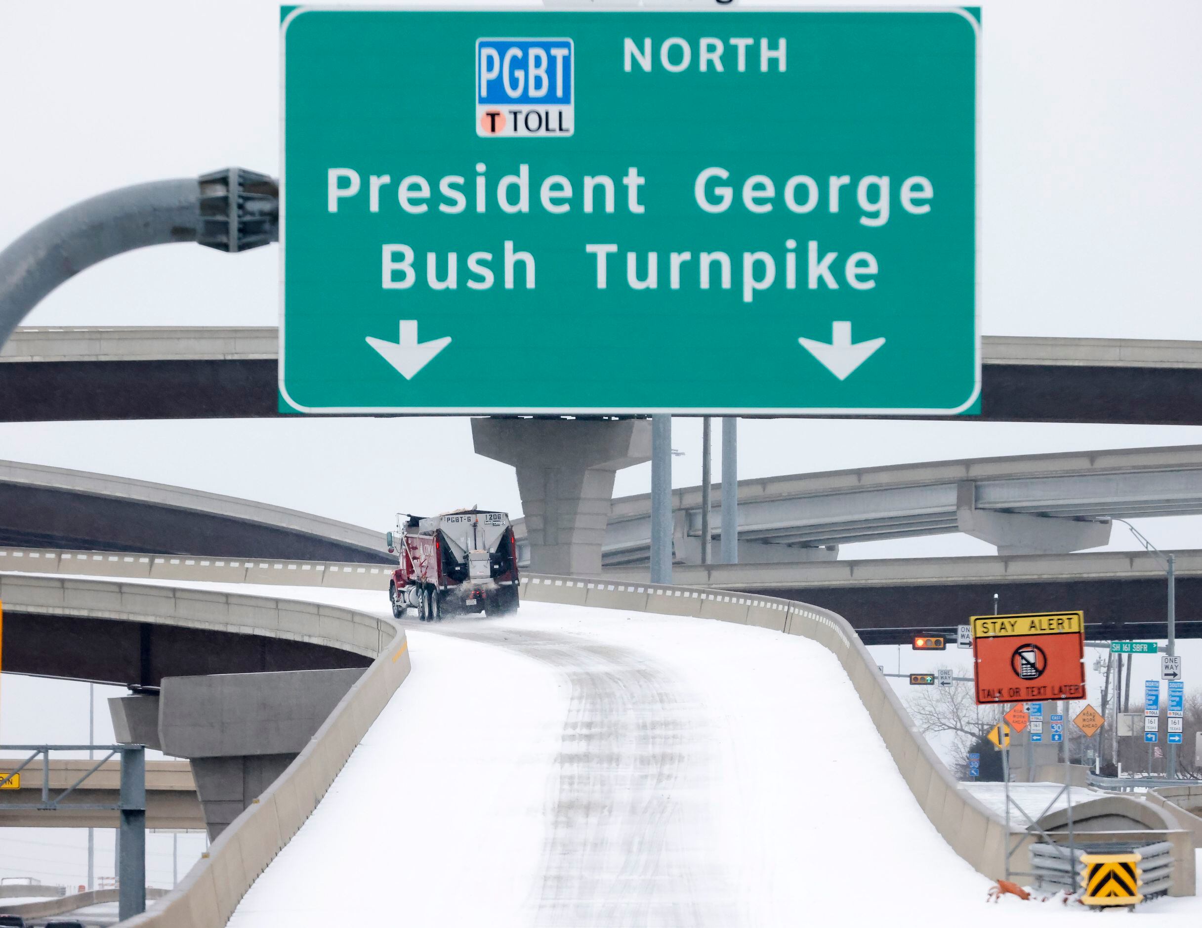 A truck spreads sand and gravel over an accumulation of sleet on a Bush Turnpike ramp from...