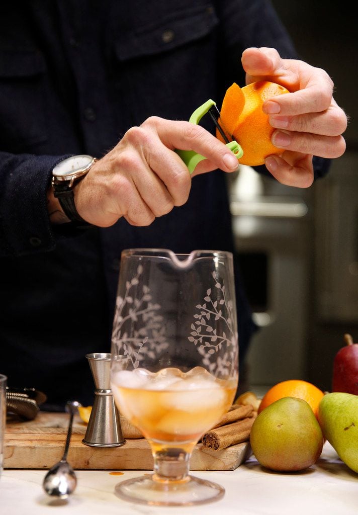 Alex Fletcher, beverage director of the Dog and Pony Show Texas peels an orange for a Cinnamon Pear Old-Fashioned 