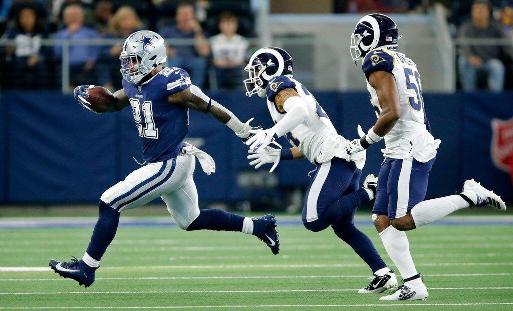FILE - Cowboys running back Ezekiel Elliott (21) runs away from Rams safety Taylor Rapp (24) and linebacker Dante Fowler (56) during the second quarter of a game at AT&T Stadium in Arlington on Sunday, Dec. 15, 2019.