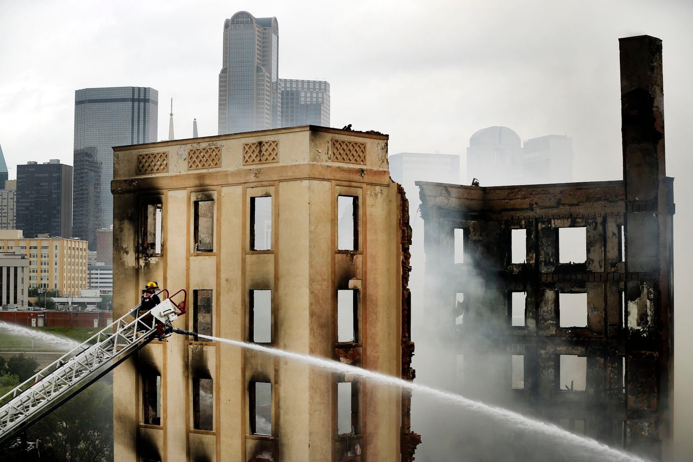 A Dallas firefighter manned an aerial hose pouring water on the destroyed historic...
