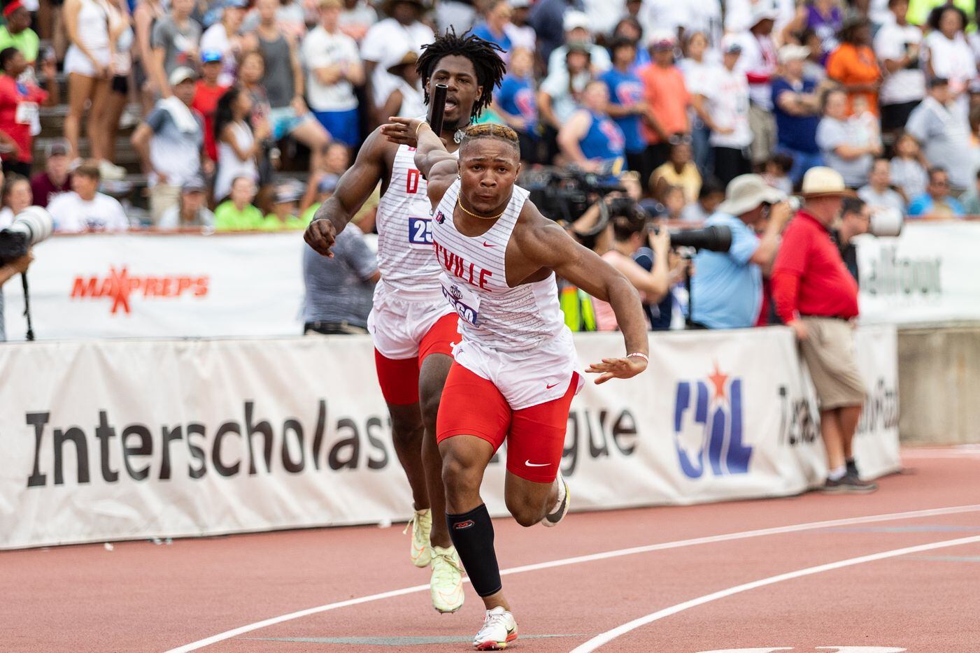 Duncanville’s Pierre Goree, left, passes the relay baton to Caden Durham at the UIL Track &...