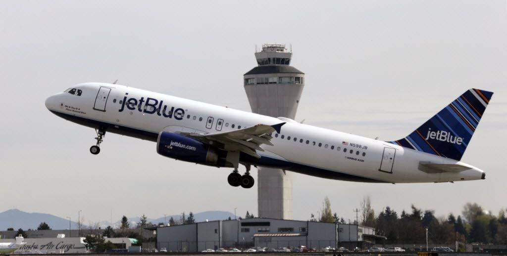 FILE photo shows a JetBlue plane taking off in view of the air traffic control tower at...