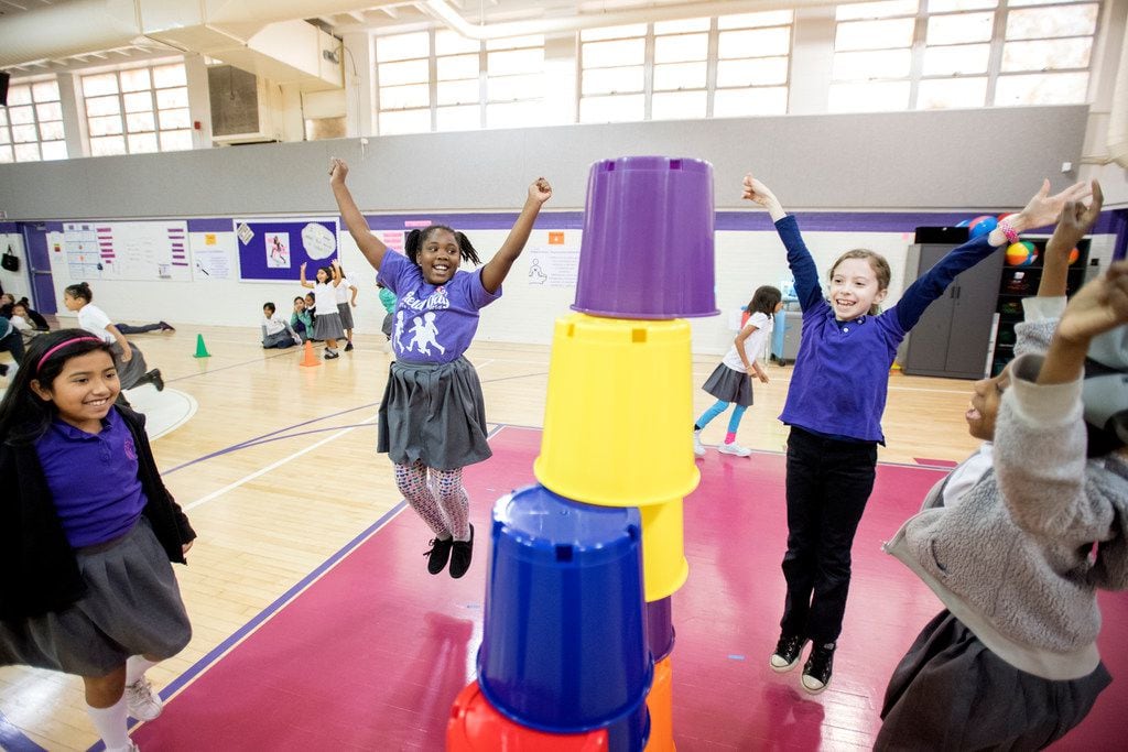 From left: Kayla Quiroga, 8; Ny'Angela Carrathus, 8; Caroline Fenlaw, 9; and Justice MacDonald, 8, celebrate after building a pyramid out of plastic buckets during a sport stacking event on Nov. 9, 2017, at Solar Preparatory School for Girls at James B. Bonham in Dallas. 