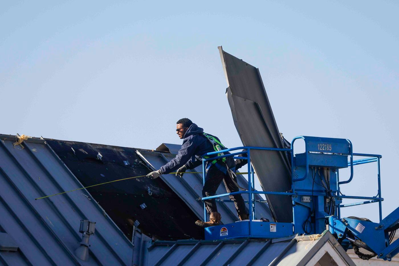 Crews work as they board up a damaged roof at Extra Space Storage in Grapevine on Wednesday,...