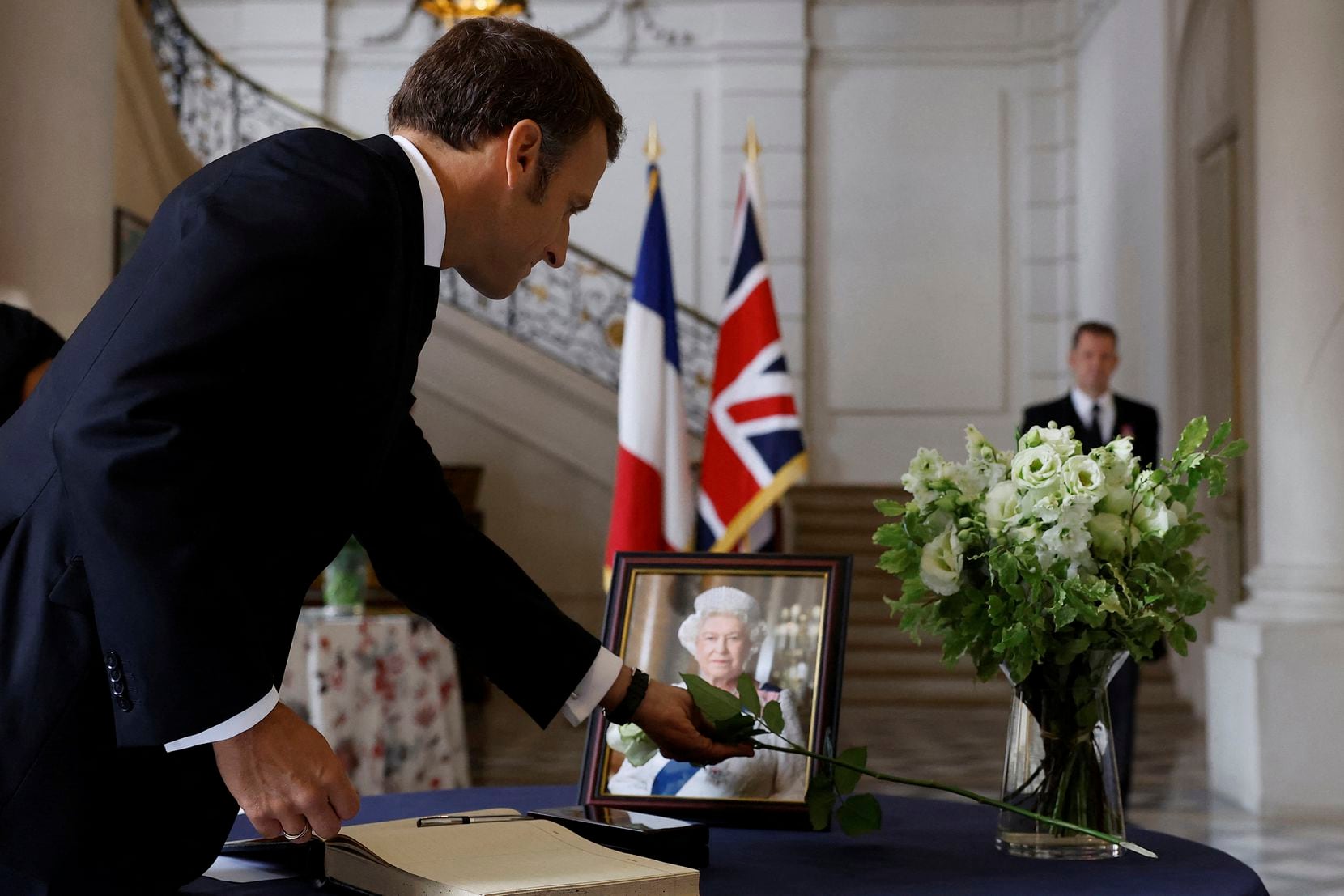 El presidente francés Emmanuel Macron coloca una rosa blanca junto a un retrato de la reina...