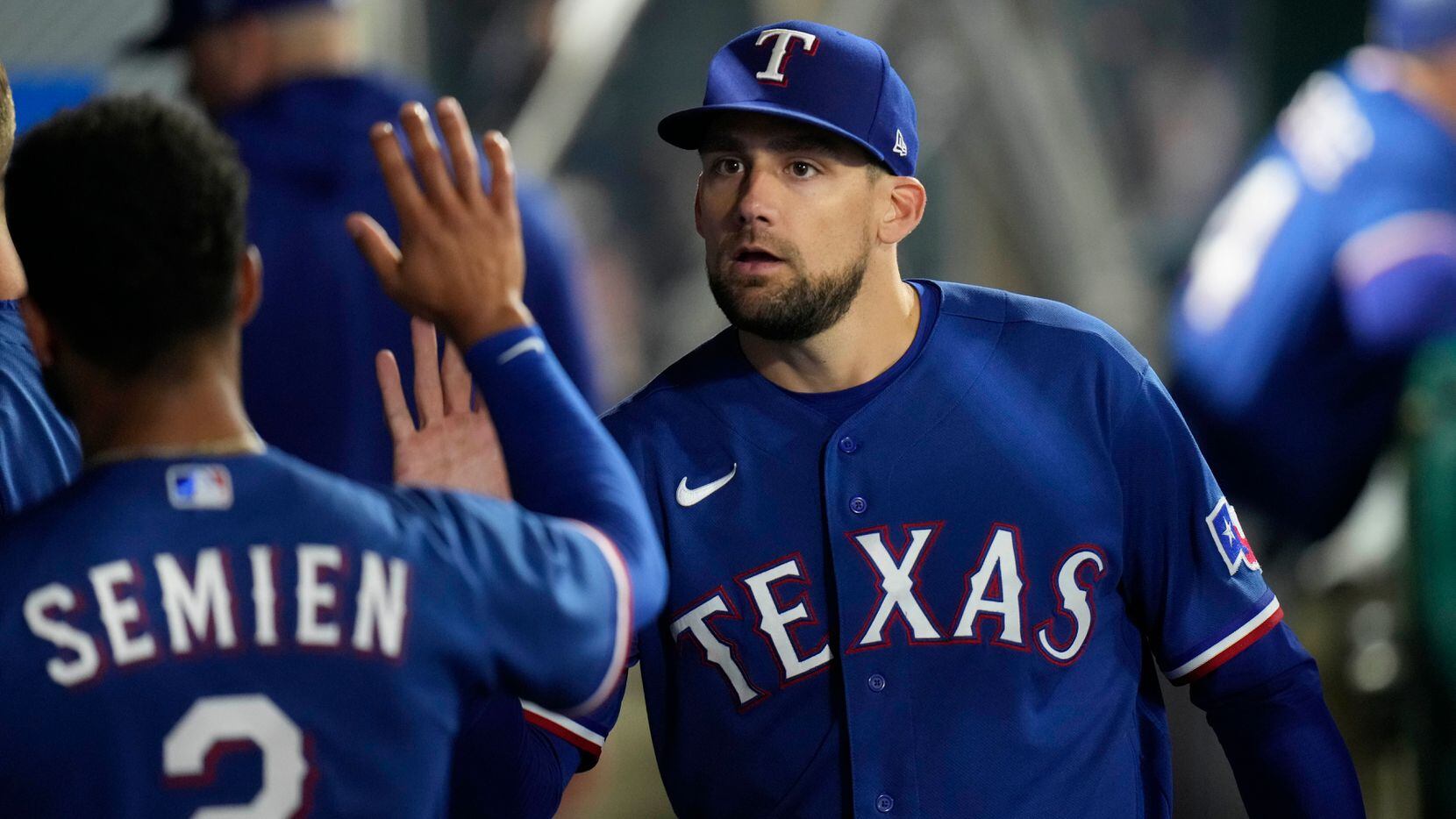 Texas Rangers starting pitcher Nathan Eovaldi, right, high-fives Marcus Semien in the dugout...