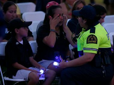 Kristy Zamarripa (center) wipes tears away as she's comforted by Dallas Bike Officer Ana...