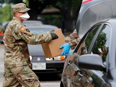 State National Guard soldiers of the 3rd Battalion, 144th Infantry Regiment from Wylie, Texas, place boxes of meals into the trunk of a vehicle as they help distribute food at a North Texas Food Bank mobile pantry distribution location in Irving, Texas, Thursday, April 9, 2020.
