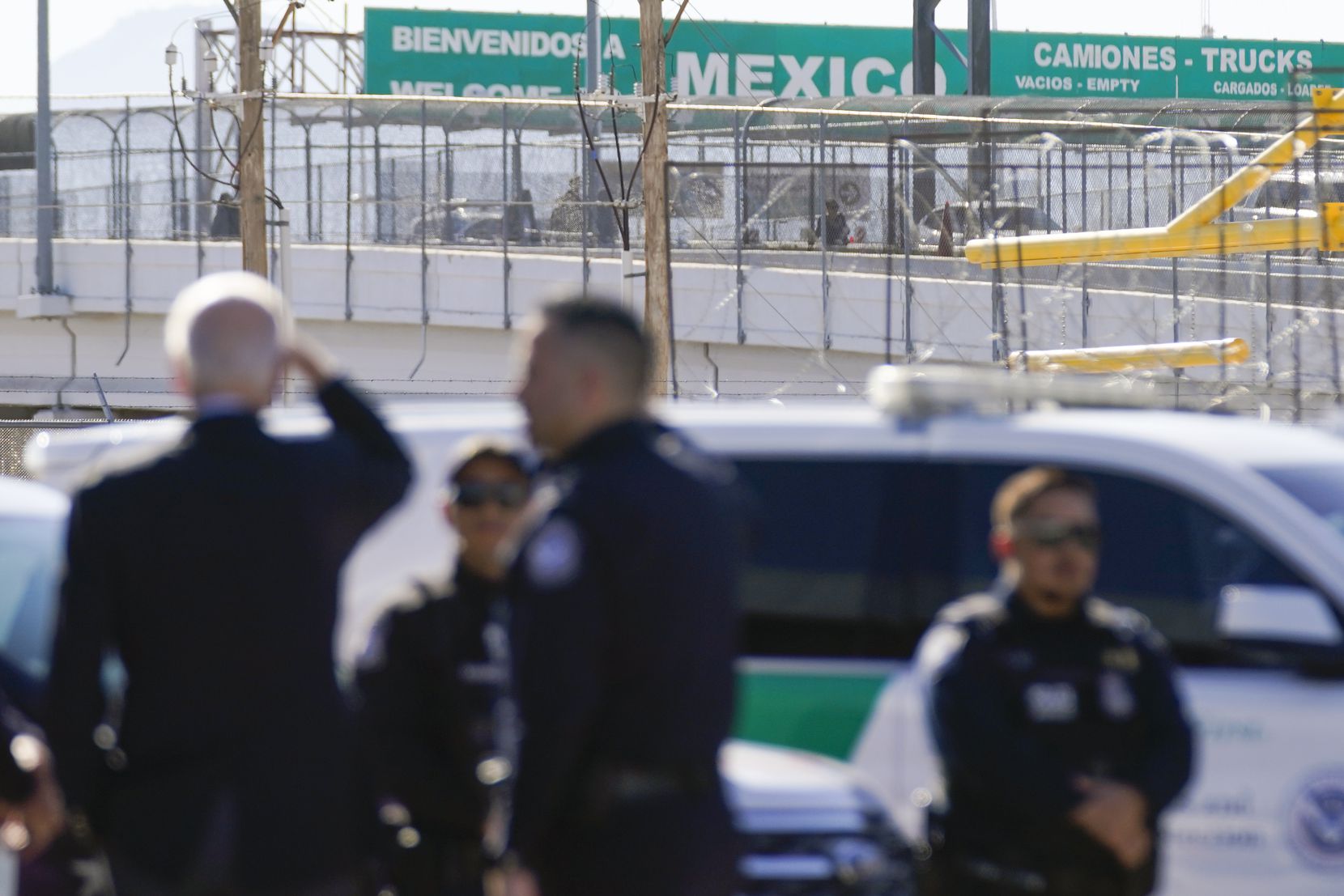 President Joe Biden, left, looks towards a large "Welcome to Mexico" sign that is hung over...