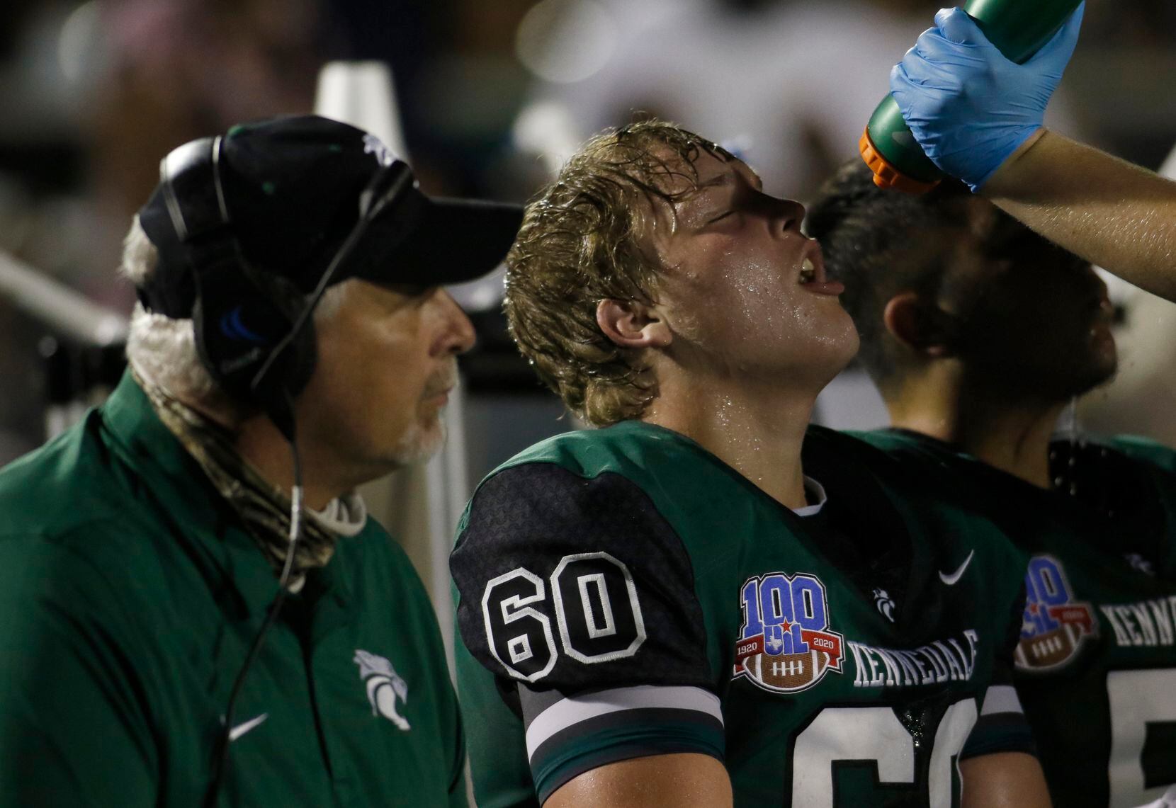 Kennedale offensive lineman Cole Shue (60) takes a water break on the team bench during...