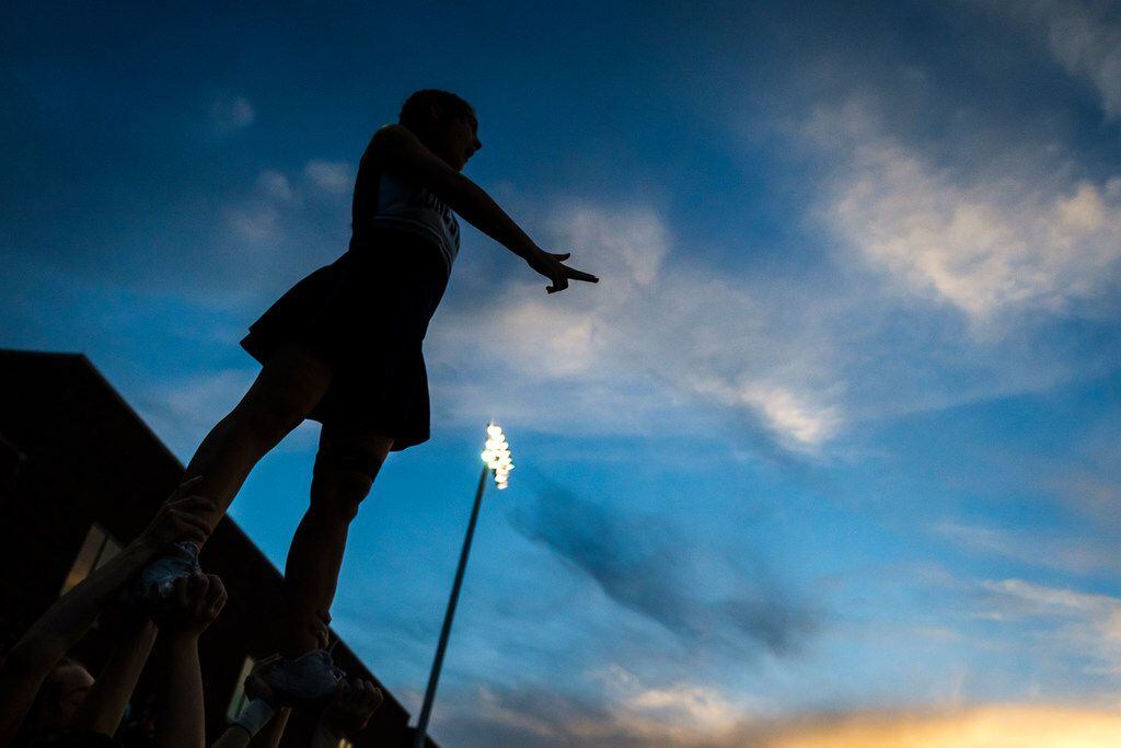 A Frisco Lone Star cheerleader is silhouetted against the sky during the opening kickoff of...