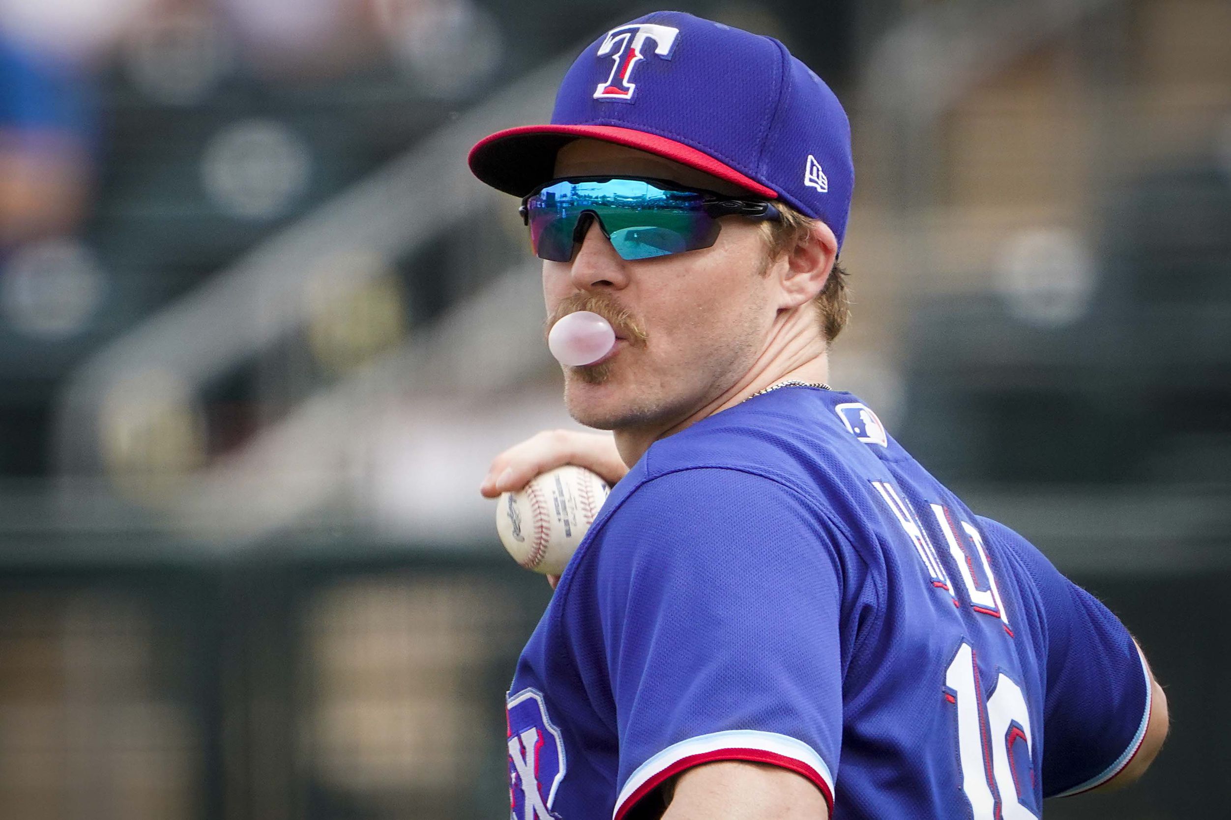 Texas Rangers third baseman Brock Holt (16) blows a bubble during a  baseball game against the