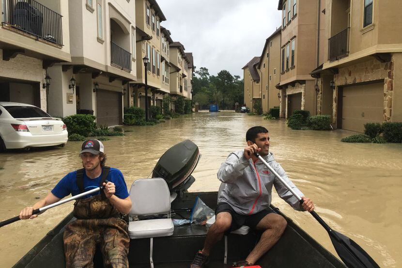 Dallas residents Josh Womack and Sammy Abdullah paddle through a row of townhomes on a...