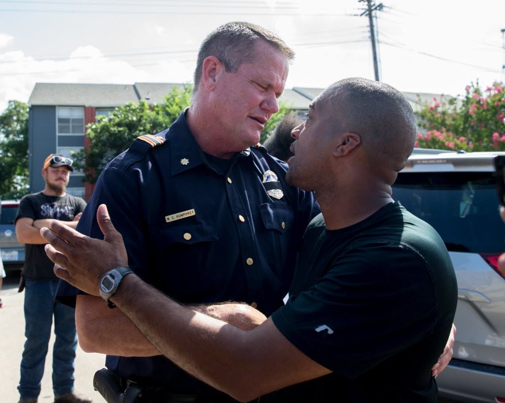 Officer W.C. Humphrey shake hands and embrace with Ty Hardaway, 44, of Dallas during the...