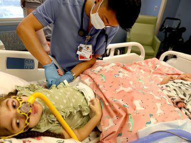 Savan Nguyen, R.N., prepares Charlotte Brooks, 5, for discharge by removing the wires and...