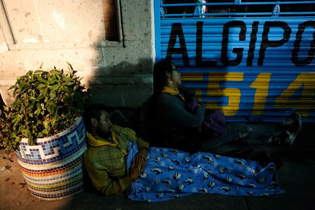 Exhausted family members waiting for news of missing relatives sleep on the sidewalk as rescue workers labor to reach survivors trapped inside a collapsed office building in the Roma Norte neighborhood of Mexico City, in the early morning hours of Saturday, Sept. 23, 2017. A 7.1 magnitude earthquake Tuesday toppled more than three dozen buildings in the capital, leaving at least 46 people believed missing in this office building alone.