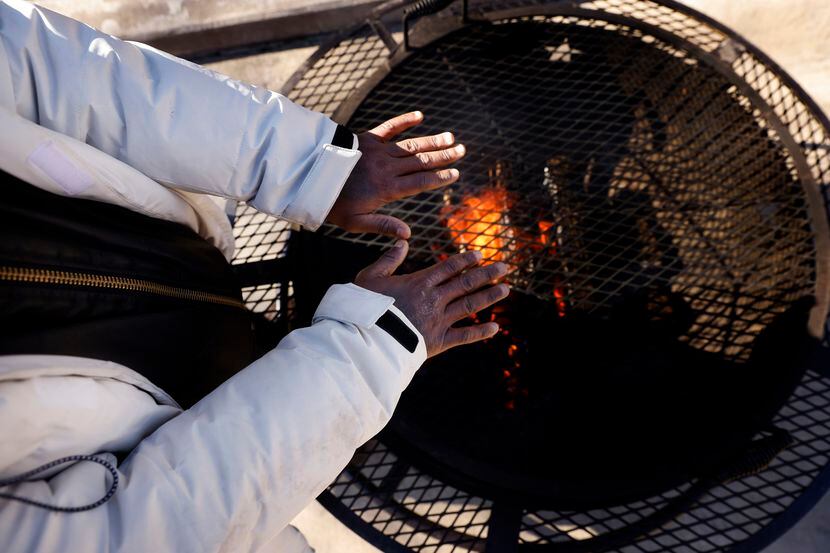 With temperatures below freezing, vendor Marquise McBride of Dallas keeps his hands warm...