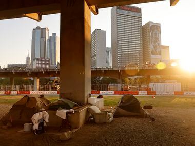 The sun sets behind a homeless encampment under the I-345 overhead in downtown Dallas, Thursday, August 26, 2021.(Tom Fox/The Dallas Morning News) 