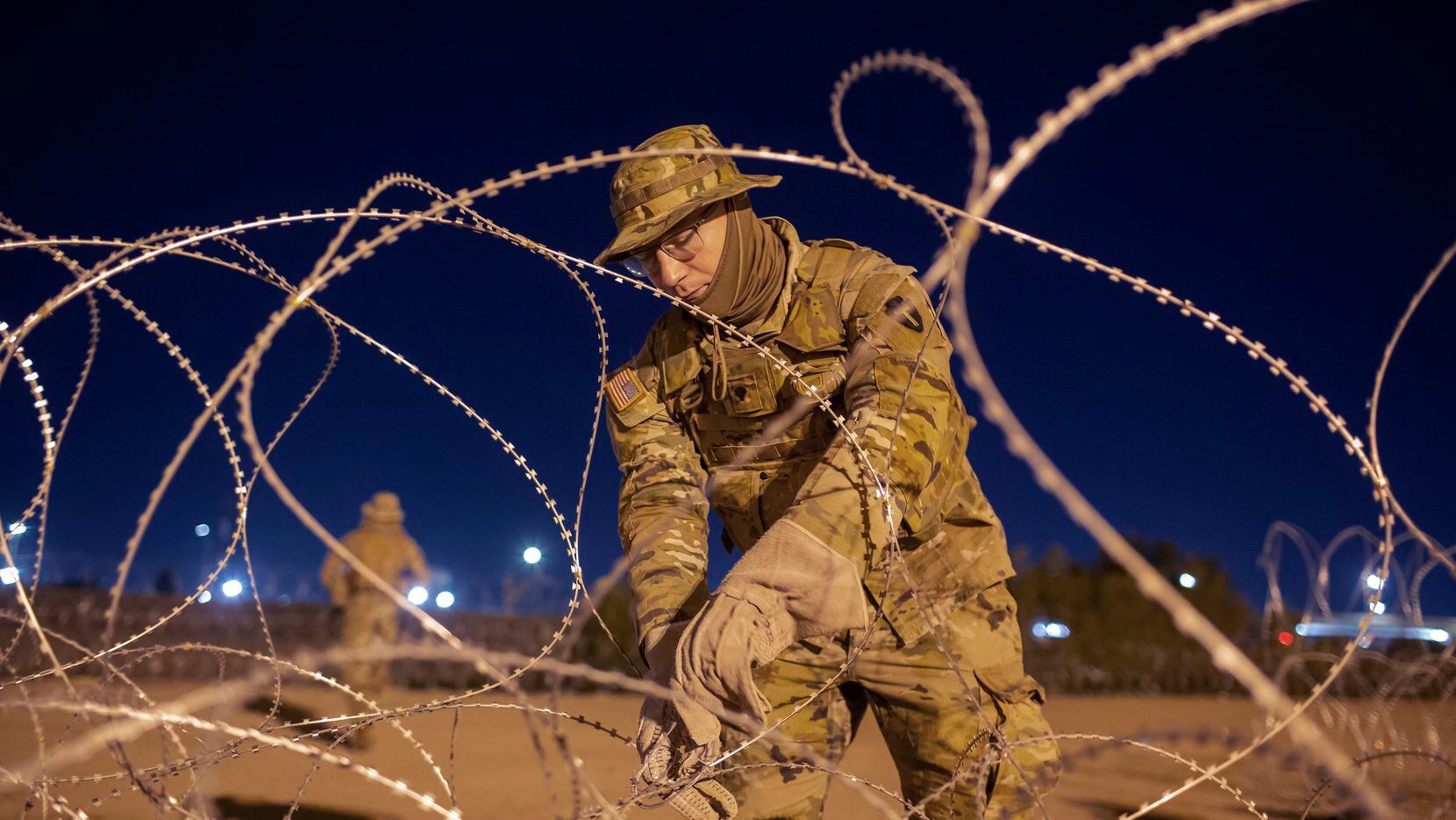 Un soldado de la Guardia Nacional de Texas ata una alambrado para frenar la inmigración por...