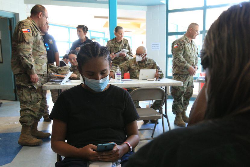Daniela Linares waits for her turn to provide information to a Texas National Guard officer...