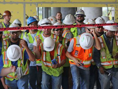 Construction workers gather during a July 18, 2017, ceremony to celebrate the topping off of...