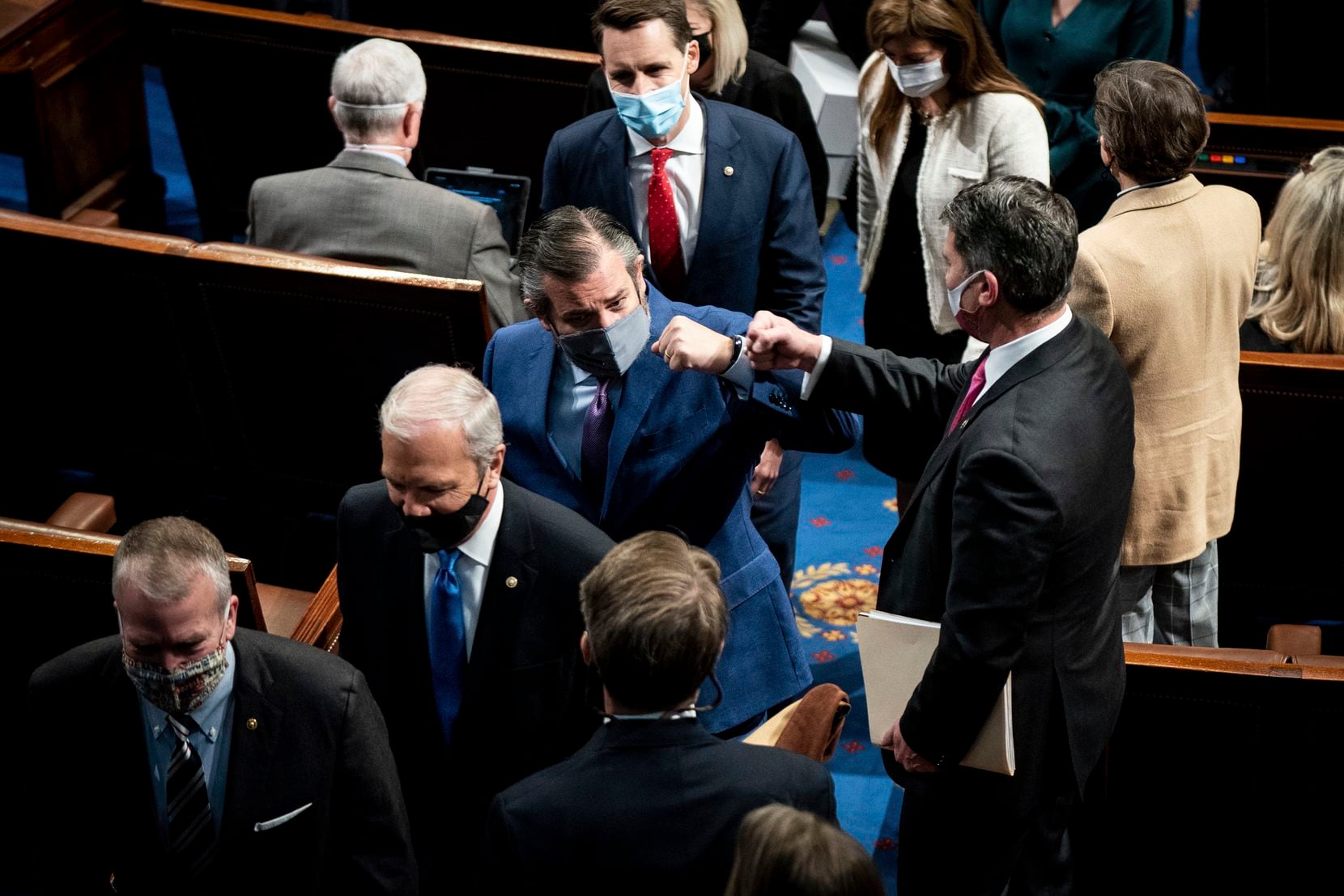 Sen. Ted Cruz, R-Texas, fist bumps with a House member as he leaves as a joint session of...