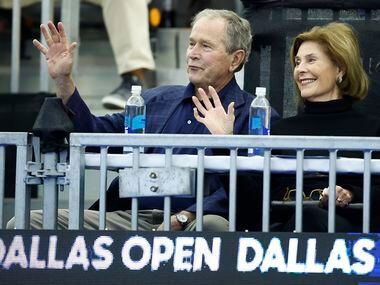 Former President George W. Bush and First Lady Laura Bush wave to fans before the start of...