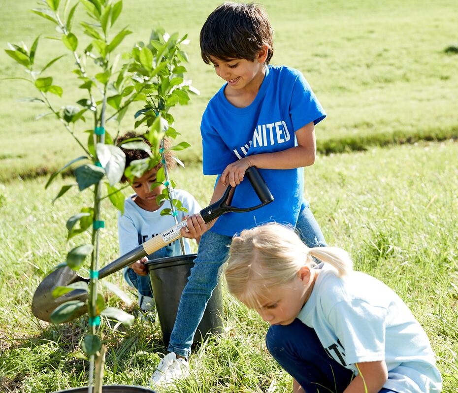 3 children plant a tree wearing Live United shirts.