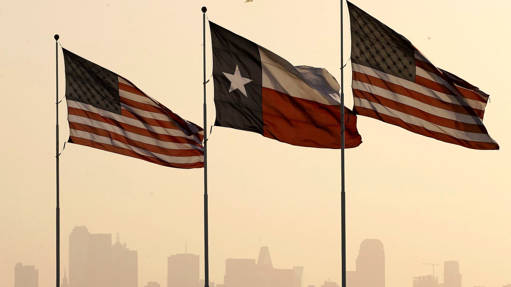 Stiff south winds blow into North Texas and downtown Dallas as Texas and U.S. flags fly...