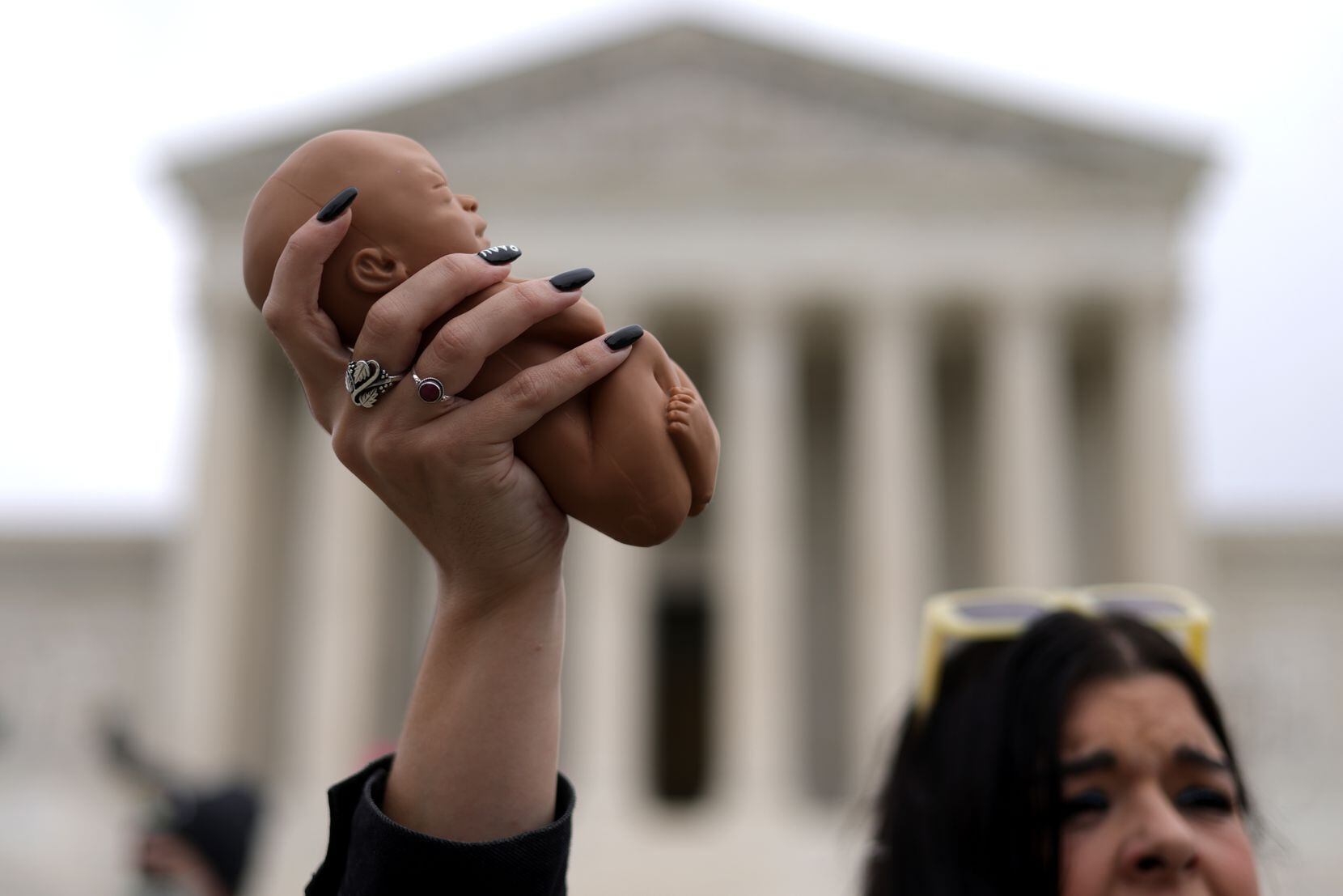 A pro-life activist holds up a baby doll during a rally for a ban on abortion in front of...