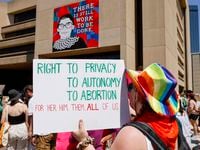 An abortion rights supporter raises a sign in front of a mural of Ruth Bader Ginsburg,...